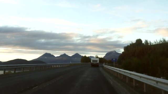 Driving on road E8 and following a RV, towards the city of Tromso, on a late evening sunset, in north Norway