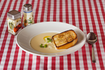 Cheese soup with croutons and herbs on the table