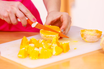 Woman housewife in kitchen cutting orange fruits