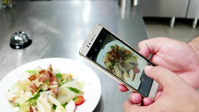 Caesar salad on mobile phone screen, chef photographs food on professional kitchen in restaurant, Photo Food mobile phone, ready meal in the cafe before serving visitors