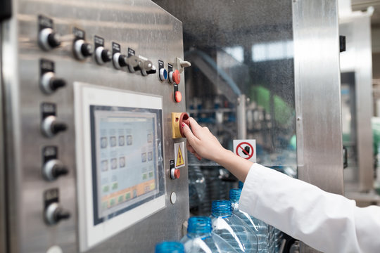 Female worker in factory checking robotic line for water bottling and packing. Inspection  of quality control. 