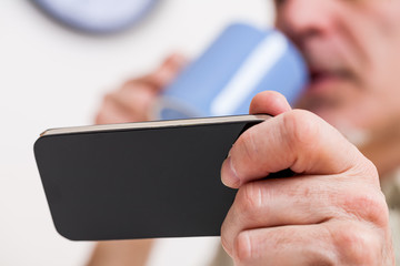 smartphone in the hand of a man having breakfast