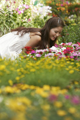 Naklejka premium Young woman leaning over to smell the flowers