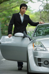 Businessman opening car door, looking at camera