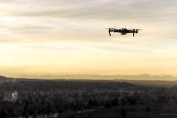 Small modern drone hovering taking picture of sunset