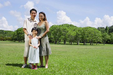 Naklejka na ściany i meble Family of three standing in field, looking at camera