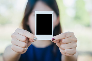 Woman hold  photo instant on hand. Blank instant photo and red clip paper heart. relationship concept.