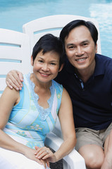 Mature couple by the pool smiling at camera