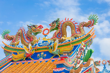 Golden dragon statue on public shrine roof, Thailand, Dragon prominently in the beautiful on blue...