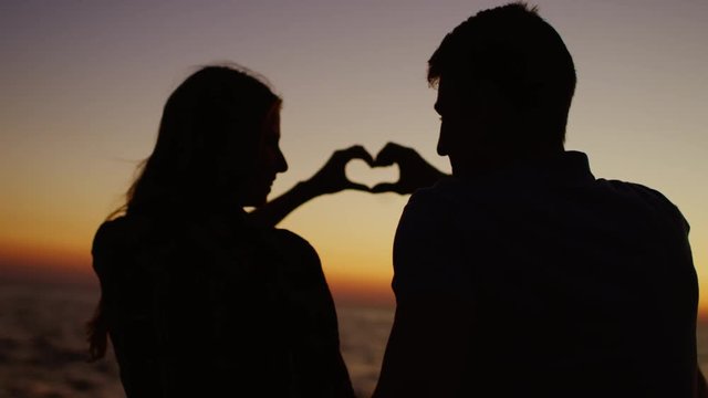 Romantic couple making heart with their hands ang looking at each other