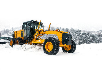 The bulldozer cleans snow on road