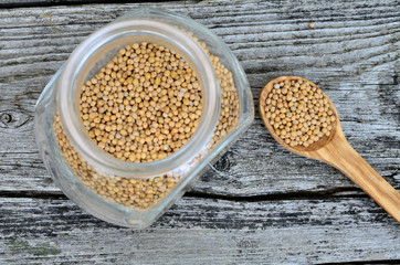 mustard seed in jar and spoon on table