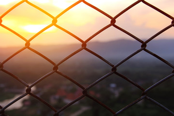 Fototapeta premium Mesh fence close-up on a blurred background of Beautiful scenery during time the sunset. The nature and the freedom concept