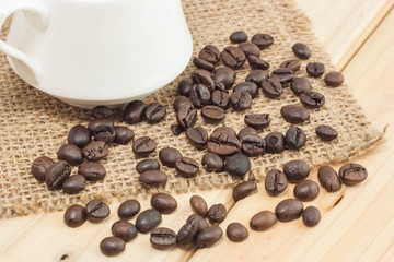 Coffee beans on sackcloth and wood background.