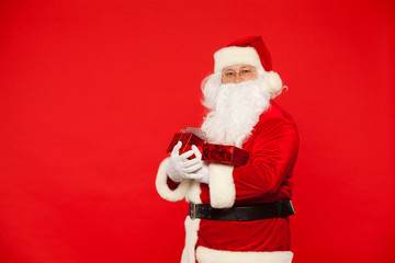 Fototapeta na wymiar Photo of Santa Claus gloved hands holding red giftbox