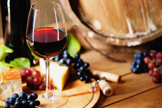 Wine glass, cheese, grapes and barrel 