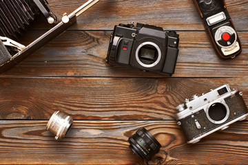 Vintage cameras and lenses on wooden background