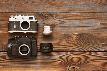 Vintage old cameras and lenses on wooden background