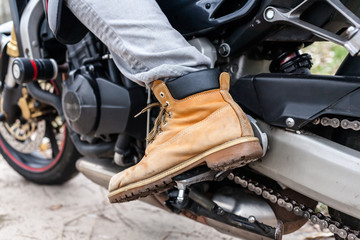 Fototapeta na wymiar Biker sitting on motorcycle, close-up view on legs.
