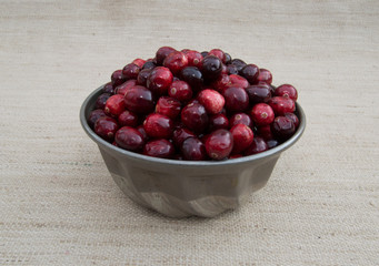 Close Up of Red and Maroon Cranberries Heaped in Vintage Tin Food Mold with Beige Woven 
Fabric Background