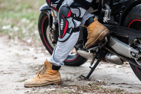 Biker sitting on motorcycle, close-up view on legs.