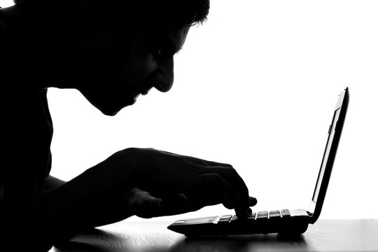 silhouette of a hacker typing on the keyboard of laptop
