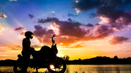 Naklejka premium Silhouette biker with his motorbike beside the natural lake and beautiful twilight sky.