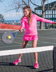 Tennis player in pink hitting ball over net.