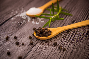 salt, rosemary and black pepper on wooden table