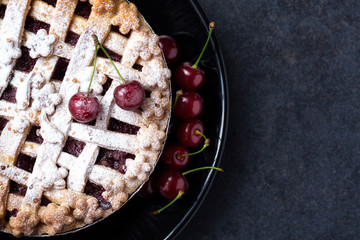 American pie with cherries, icing sugar on the plate.