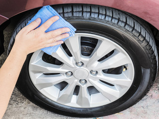 A man's hand is cleaning and waxing tire of car