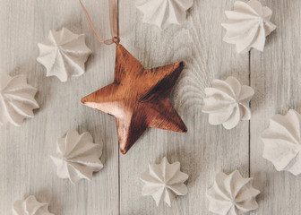 Christmas background with bronze star and airy meringues.New Year.Wooden table