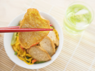 Yakisoba with chopstick and hand over bamboo pad