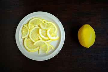 Overhead view of sliced lemon in a white dish on a wooden table, Food ingredient image