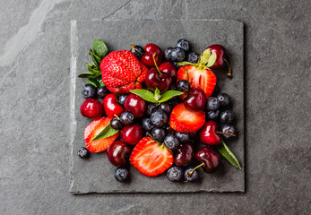 Naklejka na ściany i meble Berry mix - strawberries, cherries, blueberry on stone slate background