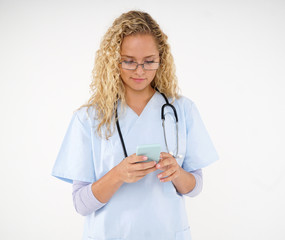 Young blonde doctor with eyeglasses and stethoscope around her neck using her mobile phone