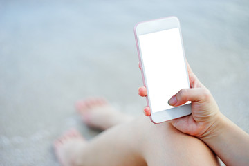 close up of woman hand using smart phone at beach.technology concept.blurred beach sea background.clipping path included.light effect added.