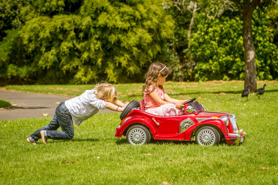 young happy children - boy and girl - driving a toy car outdoors © Alena Yakusheva