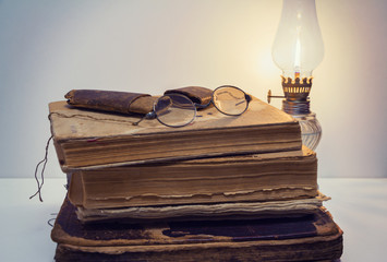 Eyeglasses and old paper case on vintage books with kerosene lantern