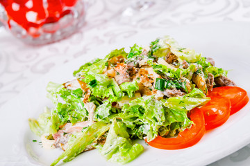 Warm salad with beef, tomato and lettuce leaves on white plate