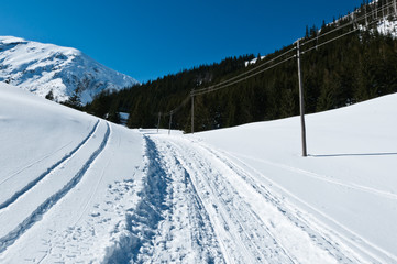 Zima w górach. Droga do schroniska w śniegu. Zaspy i śnieg na drodze. Szczyty gór w oddali. Ślady w śniegu. Dokąd prowadzi droga? Słupy telegraficzne w śniegu.