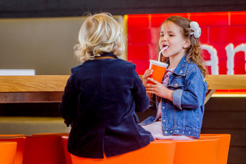 two young happy kids, boy and girl, in a cafe, drinking juice