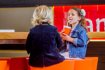 two young happy kids, boy and girl, in a cafe, drinking juice