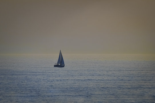 Sail boat in open sea at sunset