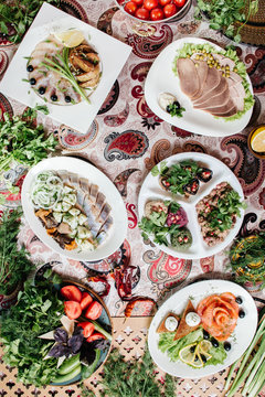 Закуски, мясо, рыба, овощи на столе.