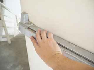 Hand is pushing/opening the emergency fire exit door