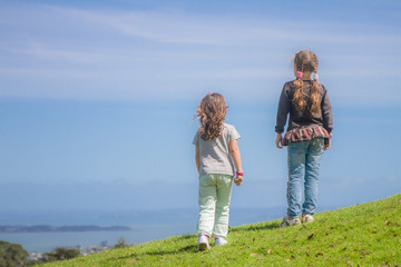 outdoor portrait of two young child girls on blue sky background