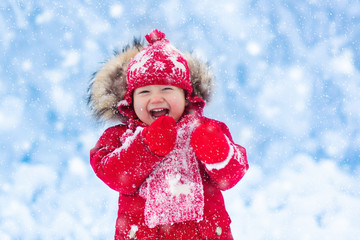 Baby playing with snow in winter.