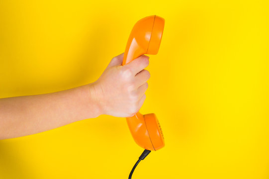 Orange Handset In Hand On A Yellow Background