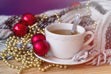Green tea in white small cup and red christmas balls and golden chain for home decoration. Christmas morning concept. Christmas breakfast